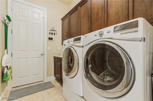 washroom with cabinets, washer and clothes dryer, and light tile patterned floors