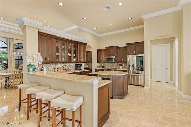 kitchen featuring decorative backsplash, kitchen peninsula, ornamental molding, appliances with stainless steel finishes, and light stone counters