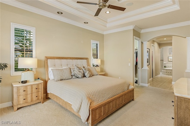 bedroom with ceiling fan, connected bathroom, decorative columns, crown molding, and light colored carpet