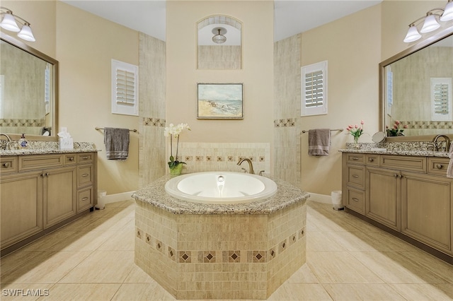 bathroom featuring vanity, a relaxing tiled tub, and tile patterned flooring