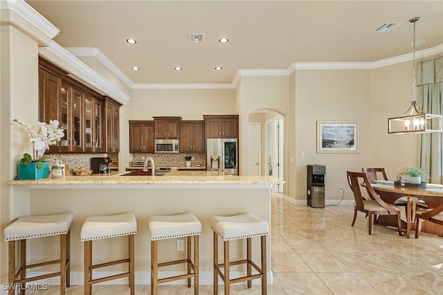 kitchen with kitchen peninsula, backsplash, appliances with stainless steel finishes, light stone countertops, and crown molding