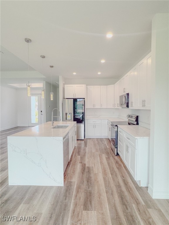 kitchen with stainless steel appliances, hanging light fixtures, light hardwood / wood-style flooring, and white cabinets