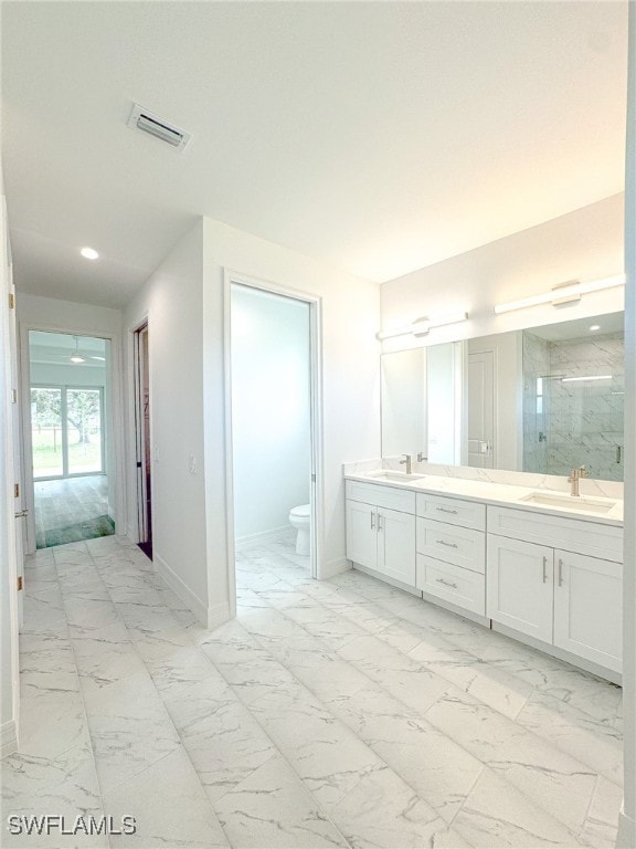 bathroom featuring a shower with door, vanity, and toilet