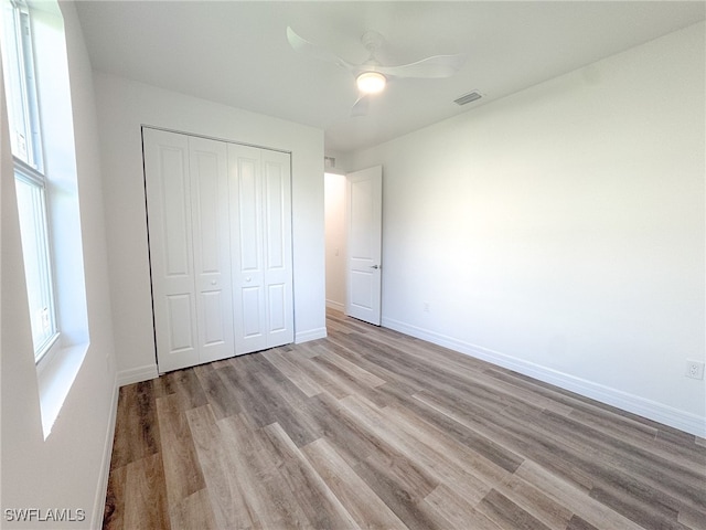 unfurnished bedroom featuring light hardwood / wood-style floors, a closet, and ceiling fan