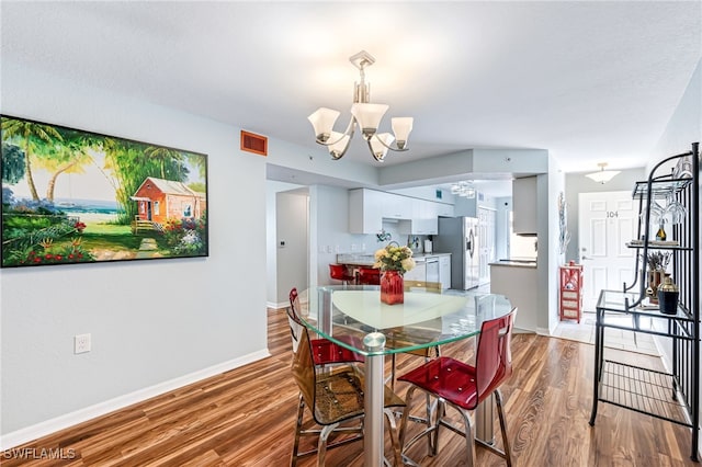 dining space featuring an inviting chandelier and hardwood / wood-style flooring