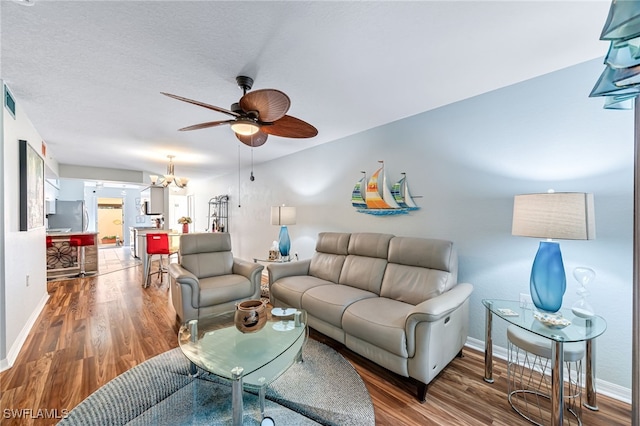 living room featuring ceiling fan with notable chandelier and hardwood / wood-style flooring