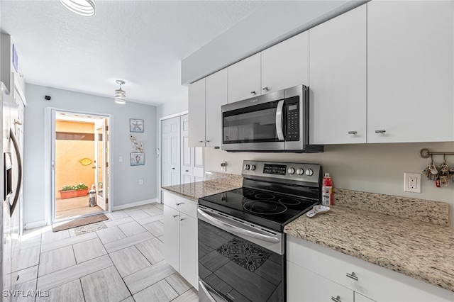 kitchen with white cabinetry, appliances with stainless steel finishes, and light stone countertops