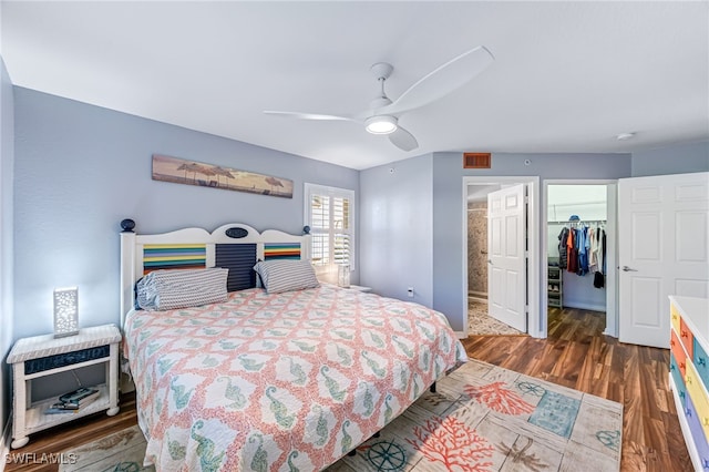 bedroom featuring dark hardwood / wood-style flooring, ceiling fan, a walk in closet, and a closet