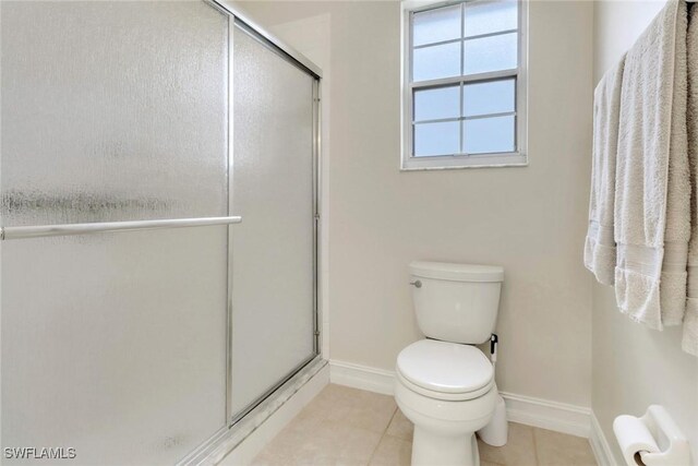 bathroom with tile patterned flooring, a shower with shower door, and toilet