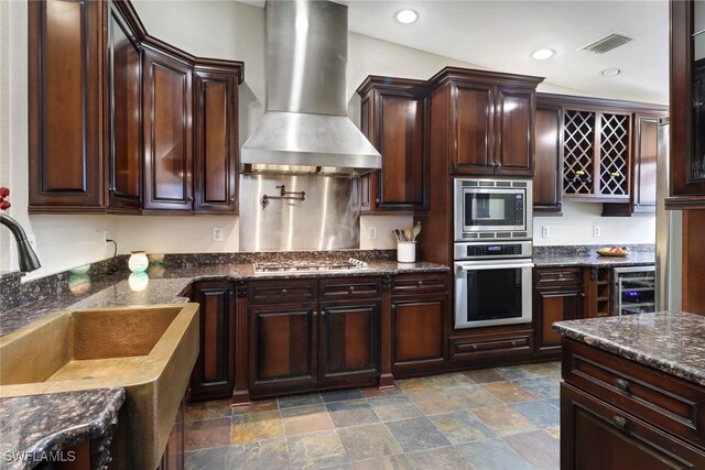 kitchen with sink, wine cooler, wall chimney exhaust hood, appliances with stainless steel finishes, and dark brown cabinetry