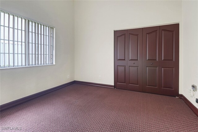 unfurnished bedroom with dark carpet and a closet