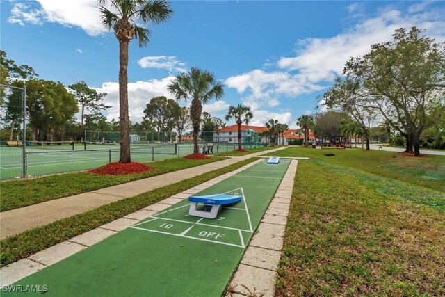 view of community with tennis court and a lawn