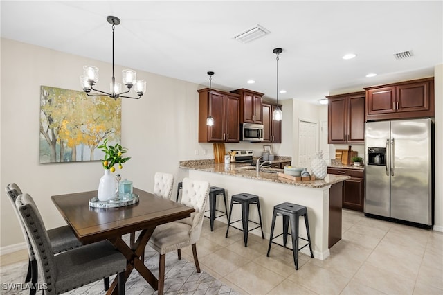 kitchen with light stone countertops, appliances with stainless steel finishes, an inviting chandelier, hanging light fixtures, and kitchen peninsula