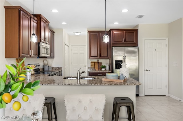 kitchen featuring decorative light fixtures, stainless steel appliances, sink, kitchen peninsula, and a breakfast bar