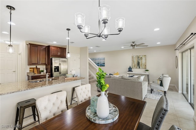 tiled dining room featuring sink and ceiling fan with notable chandelier