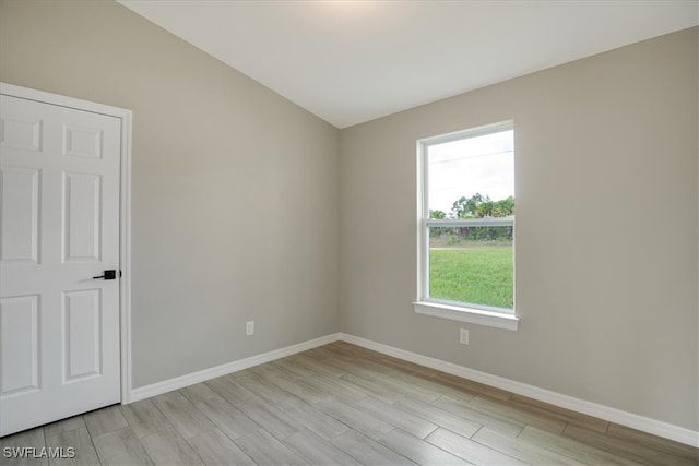 unfurnished room featuring lofted ceiling and light hardwood / wood-style floors