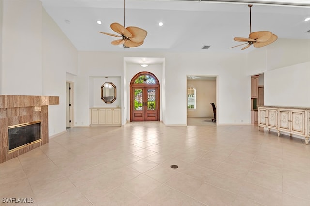 foyer entrance featuring ceiling fan, light tile patterned flooring, a fireplace, and high vaulted ceiling