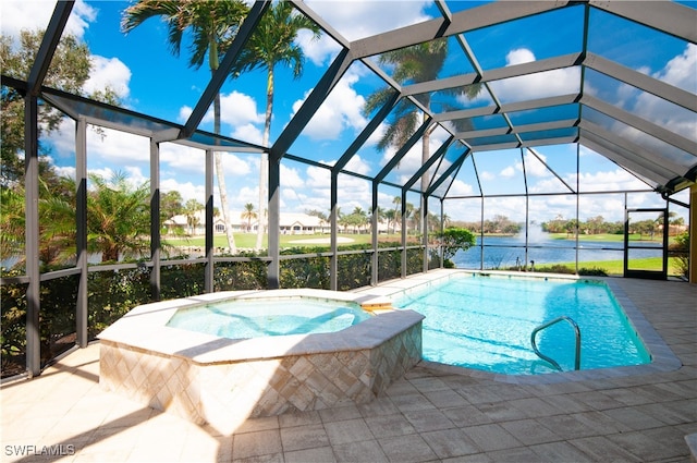 view of pool featuring an in ground hot tub, a water view, glass enclosure, and a patio area