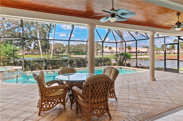 view of patio featuring a water view, glass enclosure, ceiling fan, and a pool with hot tub