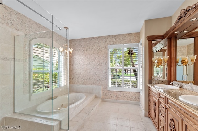 bathroom with tile patterned floors, vanity, tiled tub, and a chandelier