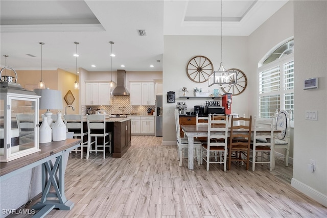 dining area with light hardwood / wood-style floors, a tray ceiling, and an inviting chandelier