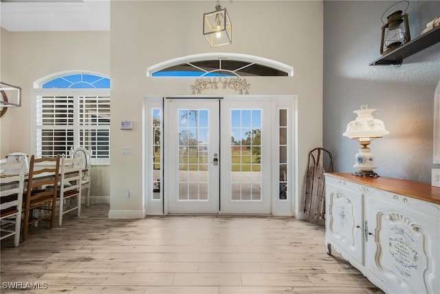 foyer featuring french doors, a high ceiling, and light wood-type flooring