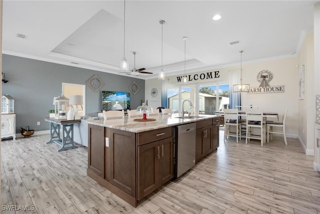 kitchen with sink, dishwasher, light wood-type flooring, decorative light fixtures, and a kitchen island with sink