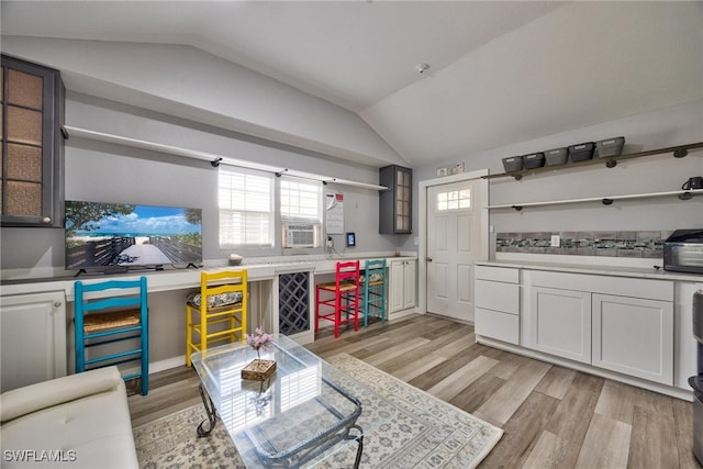 kitchen featuring cooling unit, lofted ceiling, white cabinets, and light wood-type flooring