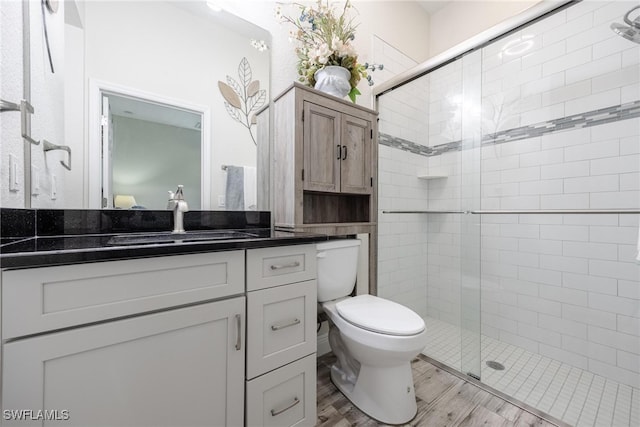 bathroom with vanity, toilet, wood-type flooring, and a shower with door