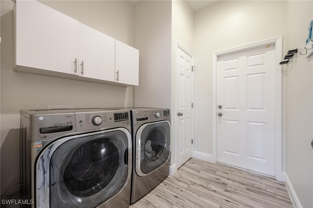 laundry area with washer and dryer, light hardwood / wood-style floors, and cabinets