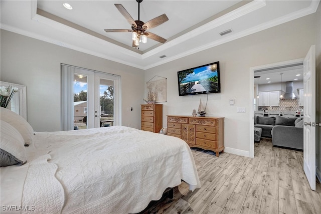 bedroom with french doors, access to exterior, a tray ceiling, light wood-type flooring, and ceiling fan