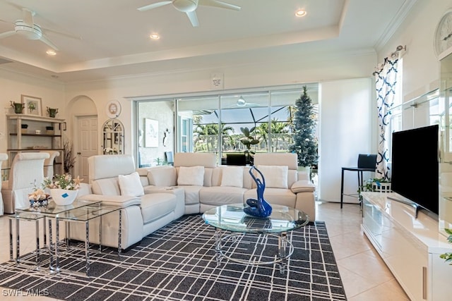 living room featuring crown molding, ceiling fan, light tile patterned flooring, and a raised ceiling