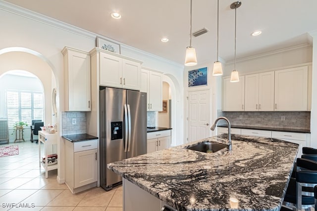 kitchen featuring light tile patterned flooring, sink, stainless steel fridge, pendant lighting, and a center island with sink