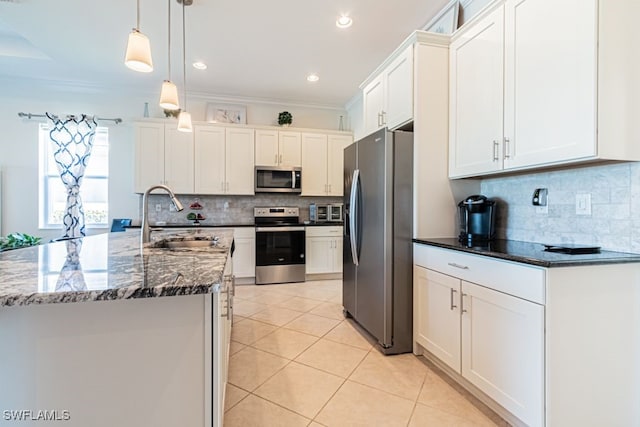 kitchen with sink, stainless steel appliances, pendant lighting, ornamental molding, and a center island with sink