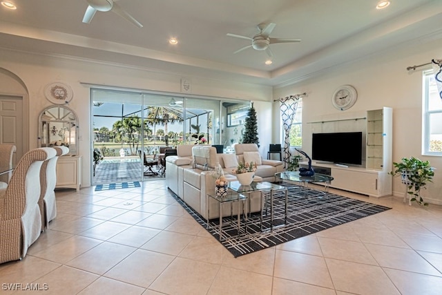 living room with light tile patterned flooring, a raised ceiling, and ceiling fan