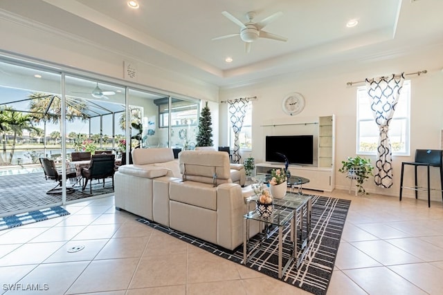 living room with light tile patterned floors, a raised ceiling, and a wealth of natural light