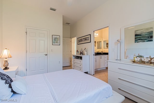 bedroom featuring ensuite bathroom and light tile patterned floors