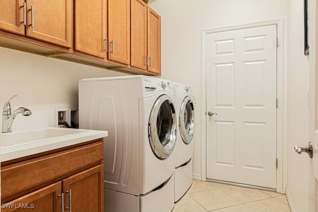 laundry area with light tile patterned floors, sink, separate washer and dryer, and cabinets