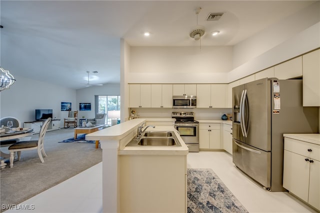 kitchen featuring sink, light carpet, stainless steel appliances, vaulted ceiling, and a kitchen island with sink