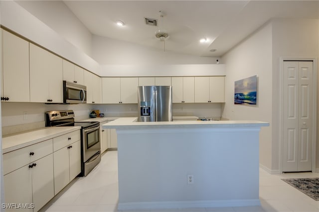 kitchen featuring a kitchen island, stainless steel appliances, vaulted ceiling, white cabinets, and light tile patterned floors