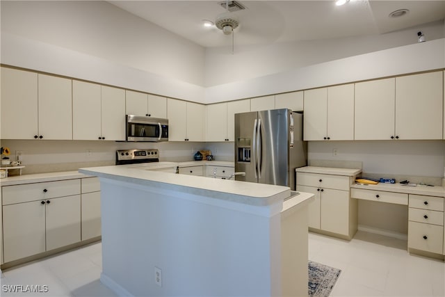 kitchen featuring a center island, vaulted ceiling, white cabinetry, light tile patterned floors, and appliances with stainless steel finishes