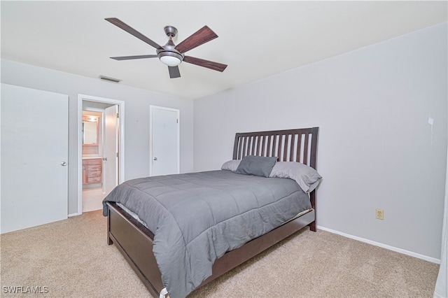 bedroom featuring connected bathroom, light colored carpet, and ceiling fan