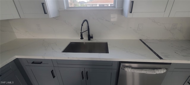 kitchen with gray cabinets, stainless steel dishwasher, sink, and light stone counters