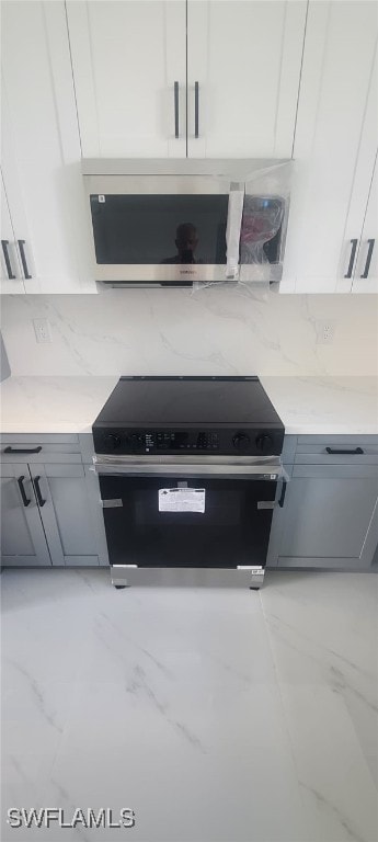 kitchen featuring white cabinetry, light stone counters, and appliances with stainless steel finishes