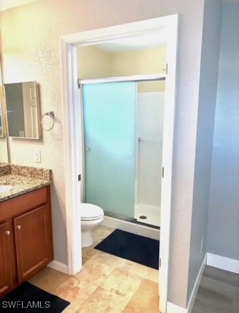 bathroom with vanity, a shower with shower door, and toilet