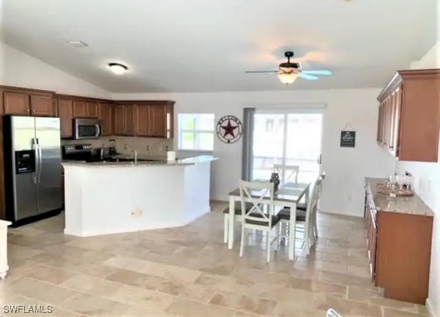 kitchen featuring ceiling fan, stainless steel appliances, lofted ceiling, and a center island with sink