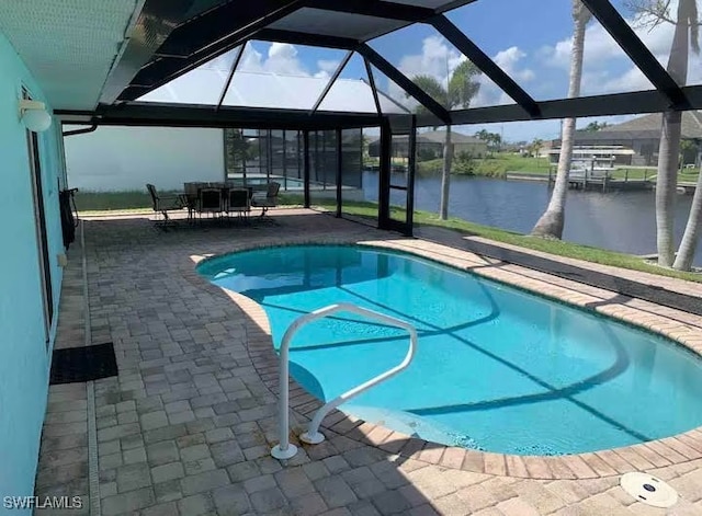 view of pool featuring a patio, a water view, and glass enclosure