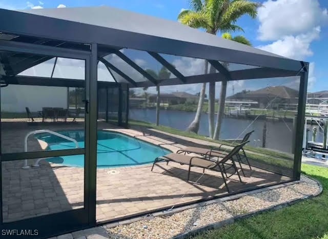 view of pool featuring a patio area, a water view, and a lanai