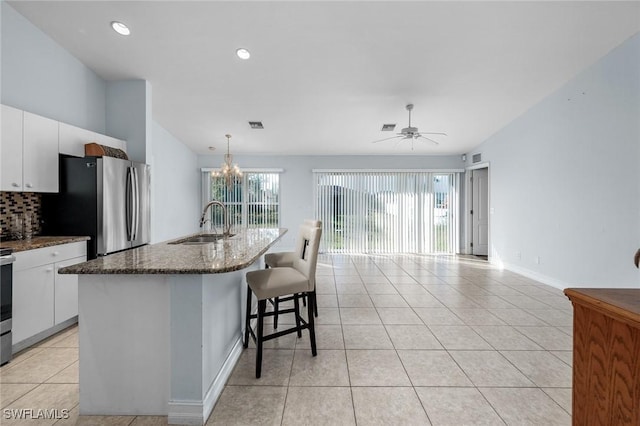 3615 4th St SW, Lehigh Acres, FL 33976 - kitchen featuring freestanding refrigerator, a sink, light tile patterned flooring, backsplash, and white cabinetry