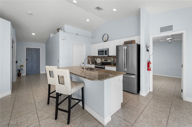 kitchen featuring an island with sink, sink, white cabinets, a kitchen bar, and appliances with stainless steel finishes